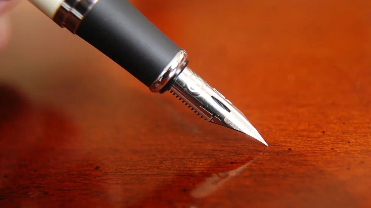 A fountain pen resting on a polished wooden desk